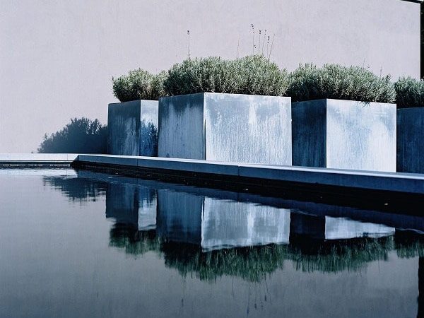 square galvanised steel planters next to garden pond